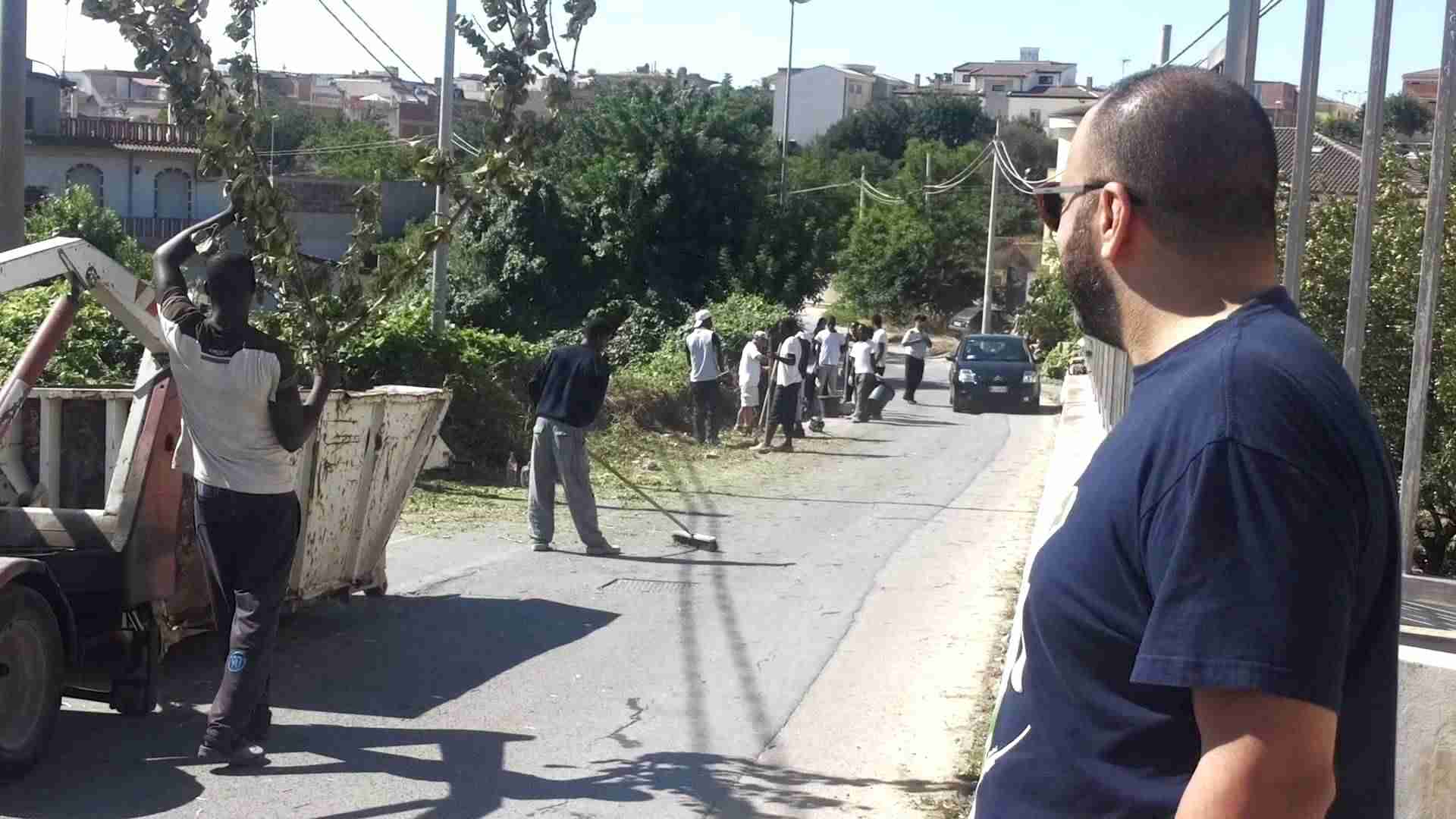 Immigrati ripuliscono la strada che porta verso contrada Perpetua